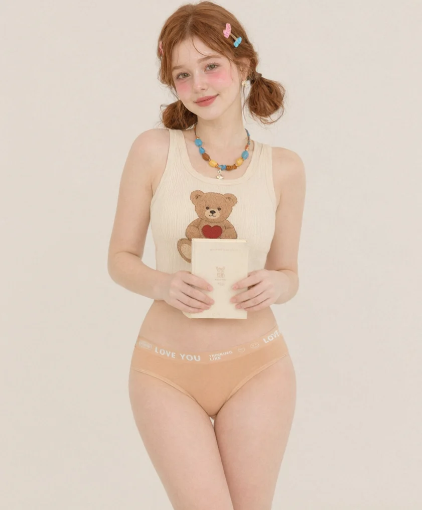 Model holding a book, wearing the peach slogan-band cotton thong DF5124